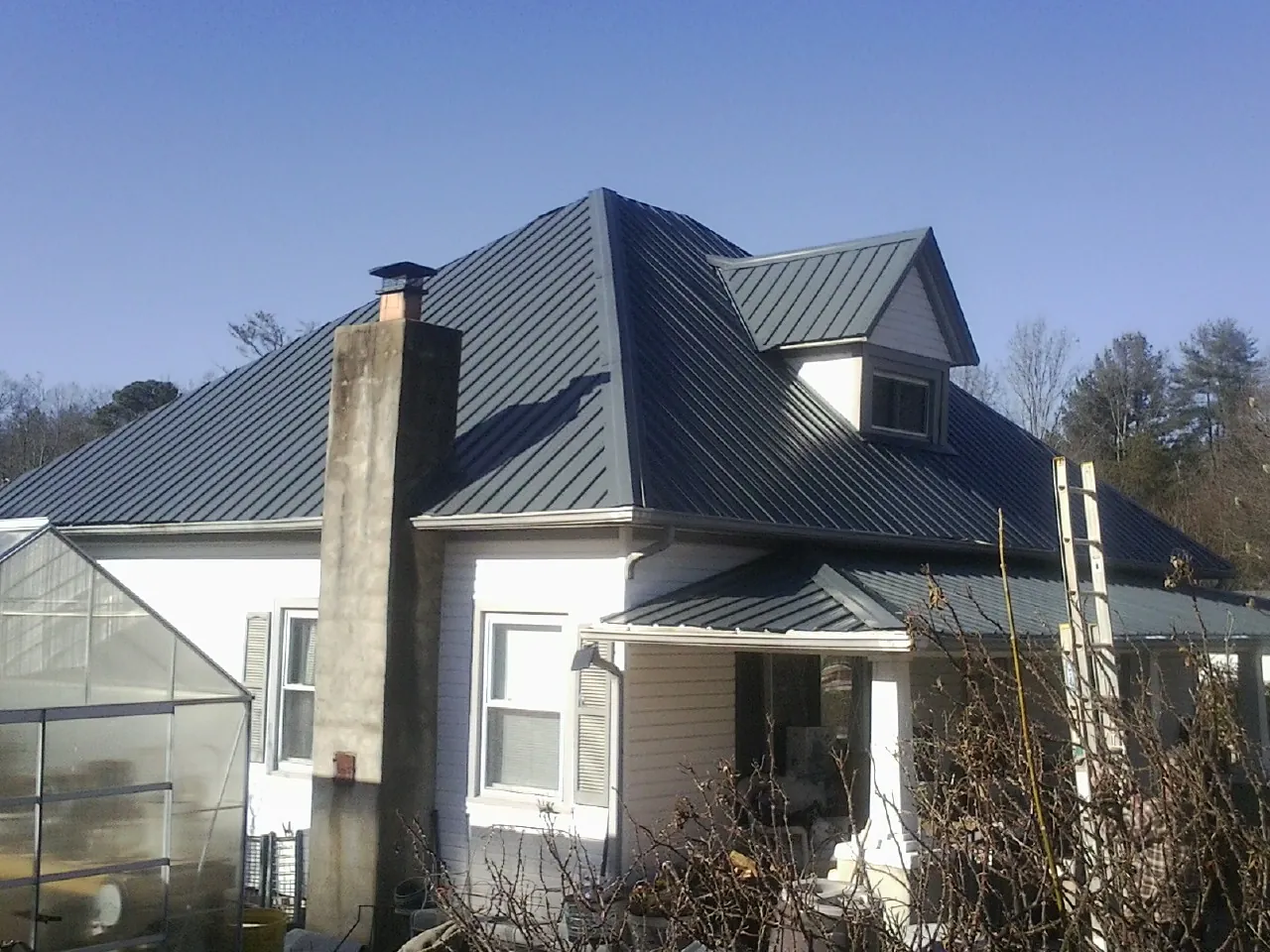 Dark blue standing seam metal roof on a white farmhouse with dormer — Slate & Tile Roof Repair by Roofing Brothers in Buckholts