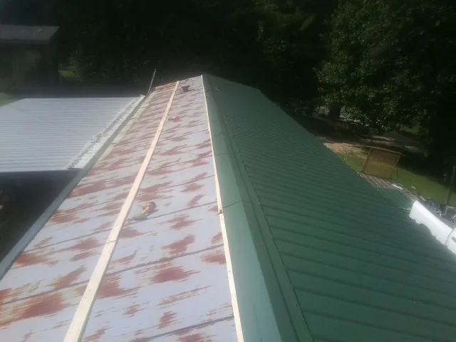 Old rusted panels beside newly installed green metal roofing — Wind Damage Roof Repair by Roofing Brothers in Buckholts