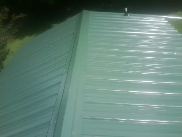 New green metal panels meeting at the ridge of a roof — Flat Roof Repair work by our crew in Buckholts