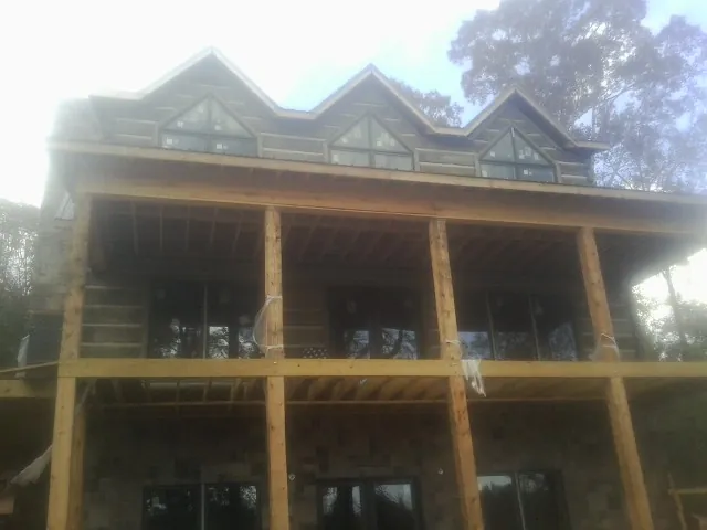 Dormers and porch framing on a large log home under construction — Roof Coating work by our crew in Buckholts