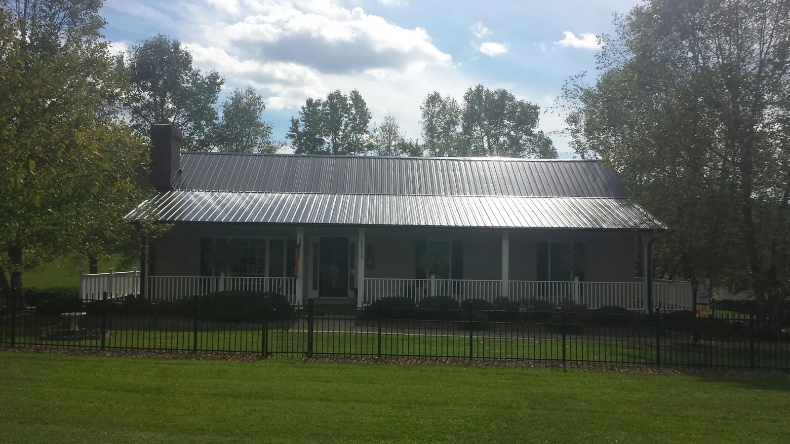 Gray metal roof on a brick ranch with a full width front porch — Gutter Guard Installation work by our crew in Buckholts