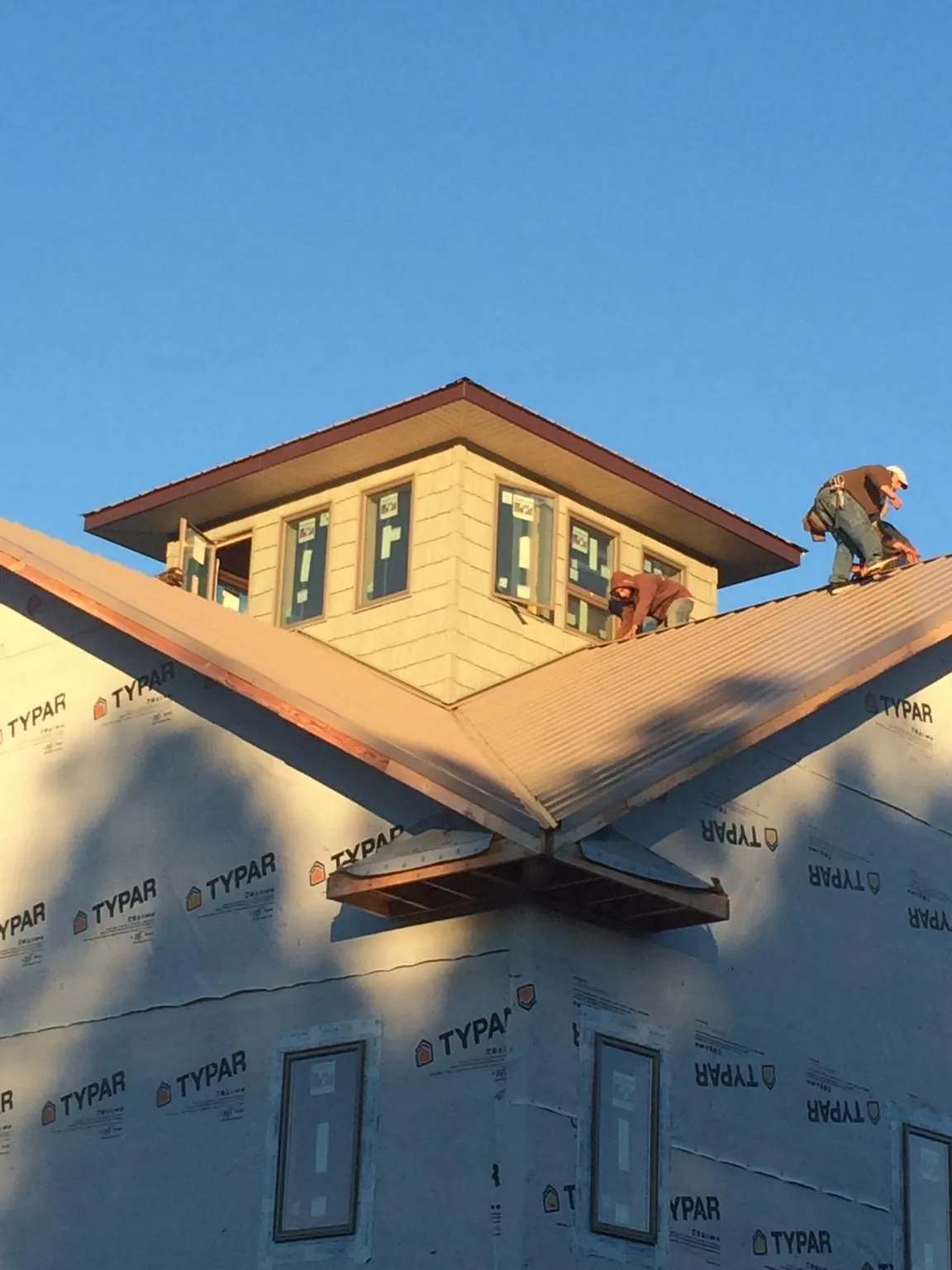 Roofers working around a rooftop cupola on a new metal roof at sunset — Roof Waterproofing in Buckholts by Roofing Brothers